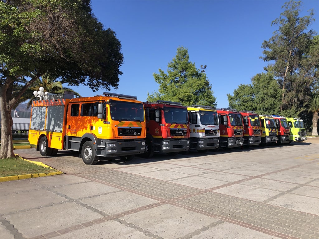 Carros bomba olitek en varios colores desde naranja, rojo y blanco alineados en el campus de bomberos de chile